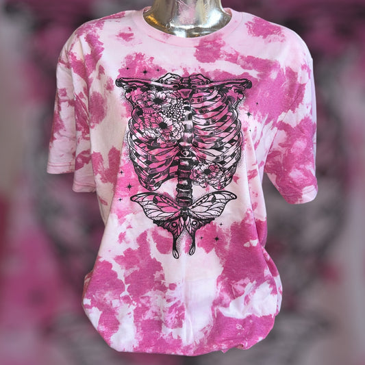 A pink and white tie-dye t-shirt with a large black skeleton rib cage and butterfly graphic on the front, displayed on a mannequin torso.