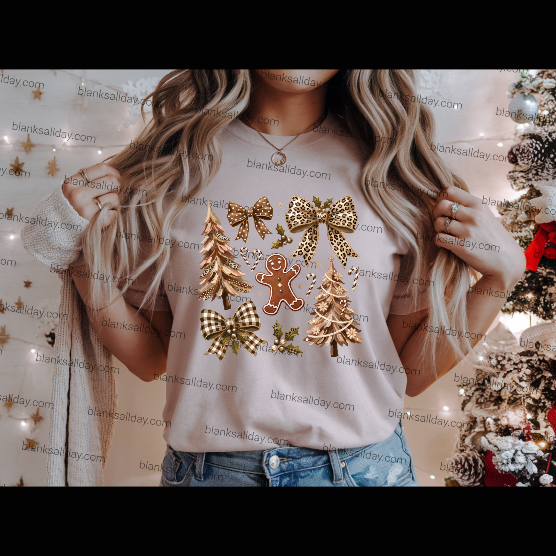 A woman wearing a light beige graphic t-shirt with a Christmas print featuring gold bows, checkered bows, pine trees, and a gingerbread man, paired with blue jeans.