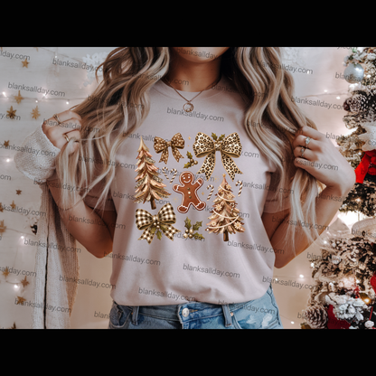 A woman wearing a light beige graphic t-shirt with a Christmas print featuring gold bows, checkered bows, pine trees, and a gingerbread man, paired with blue jeans.